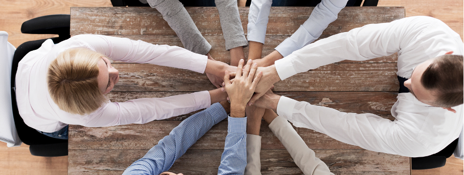 Equipe de collaborateurs qui joignent leurs mains ensemble au milieu d'une table