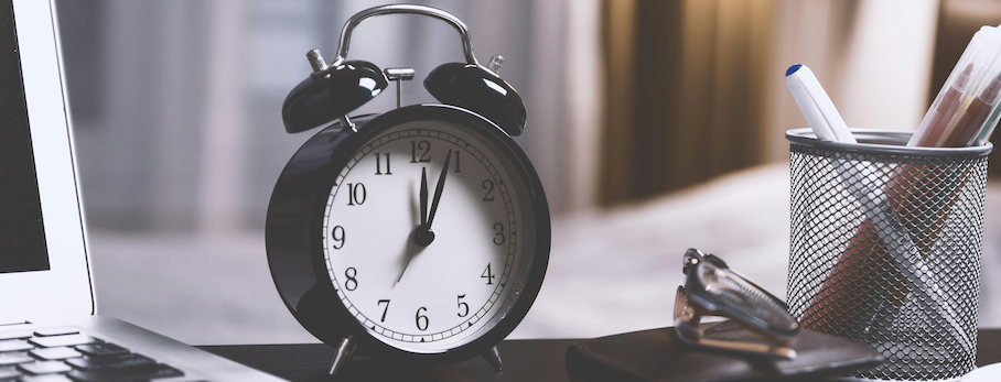 horloge noir sur un bureau à côté d'un ordinateur